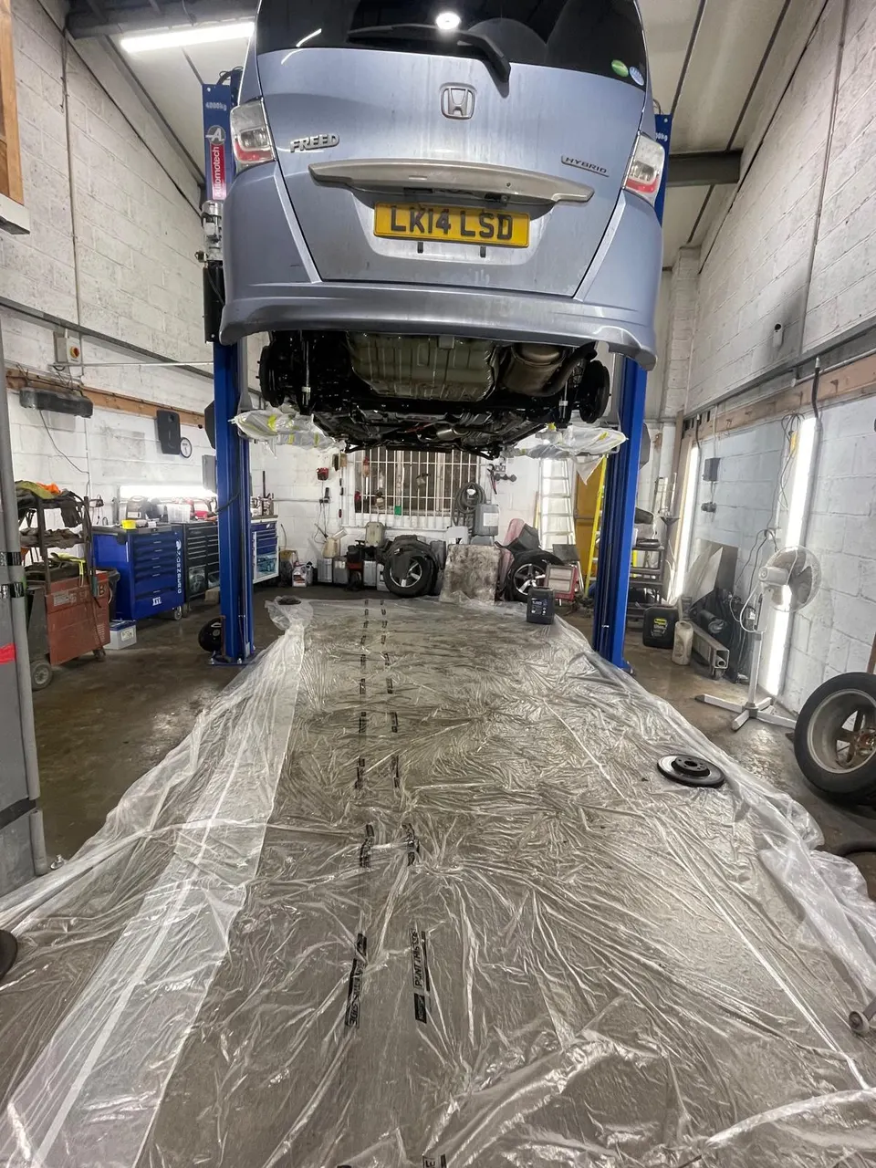 Honda Freed on the lift with the floor sheeted, ready for Lanoguard