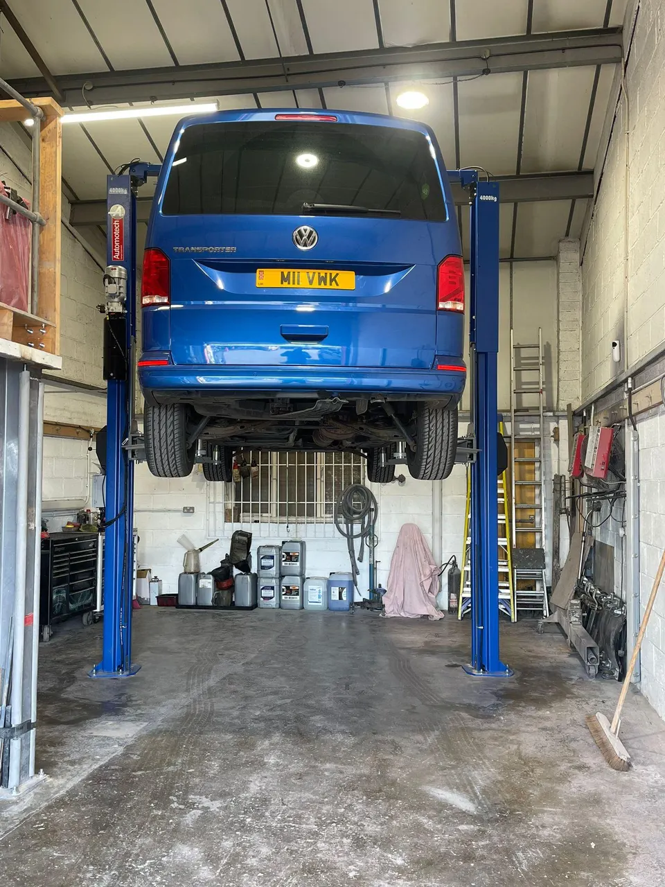 Blue VW Transporter raised on the two-post lift